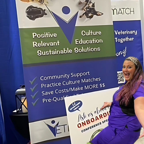 Vetmatch stand with the words positive culture, relevant education, sustainable solutions, community support, and more. VetMatch representative, stands in front in purple scrub